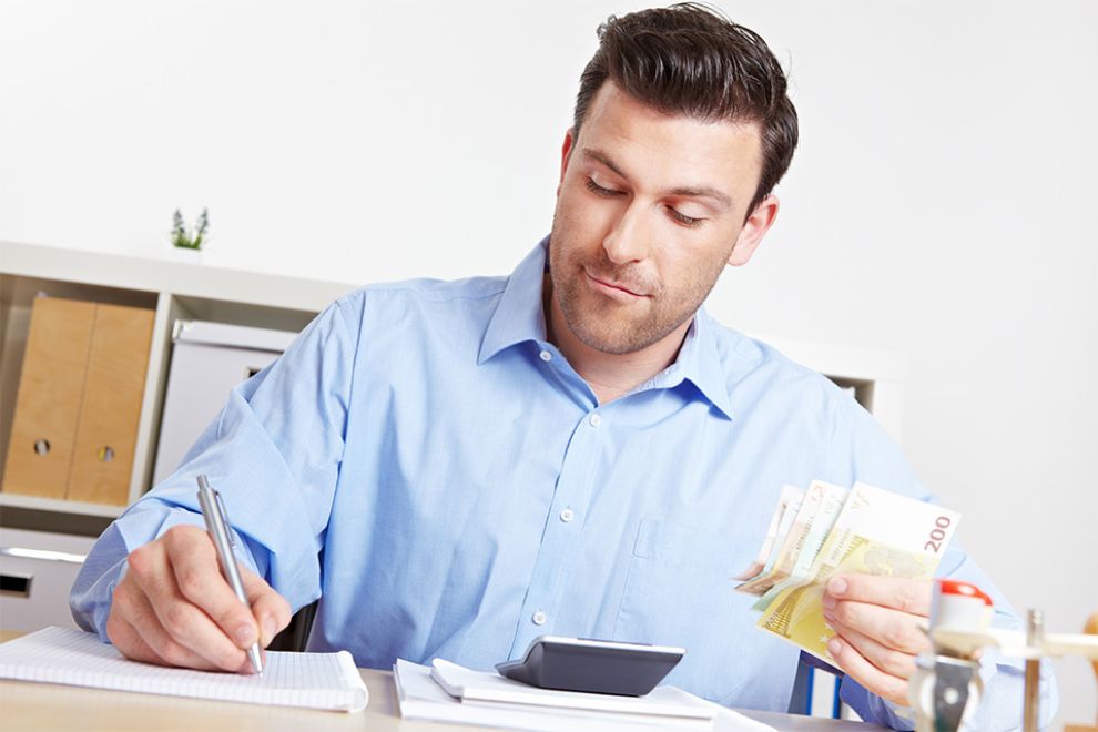 Mann mit Stift und Geldscheinen in den Händen